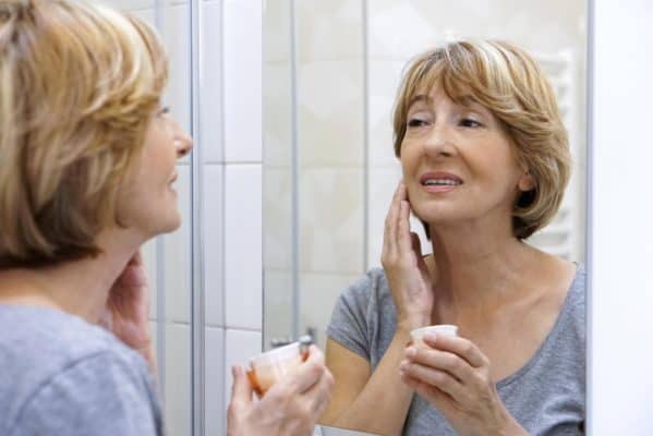 woman looking at her face on the mirror